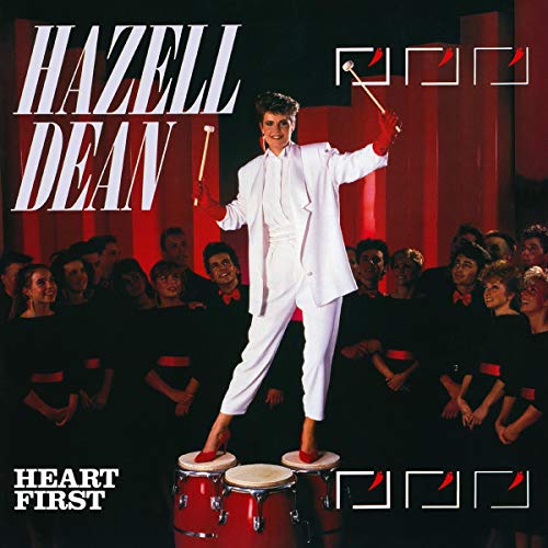 Album cover: man in white suit on red drums, surrounded by choir, red-lit background.