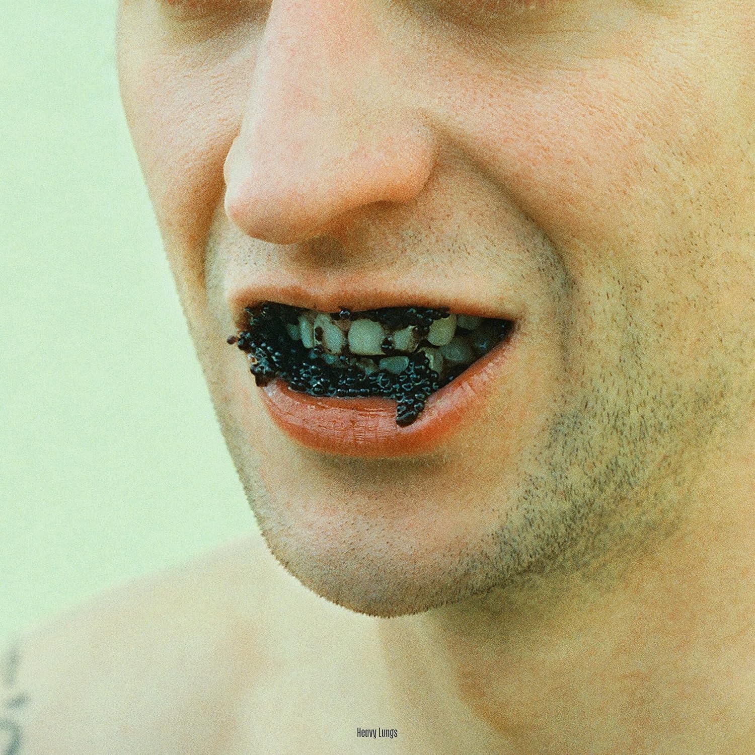 Album cover: close-up of a person with black caviar in their mouth.