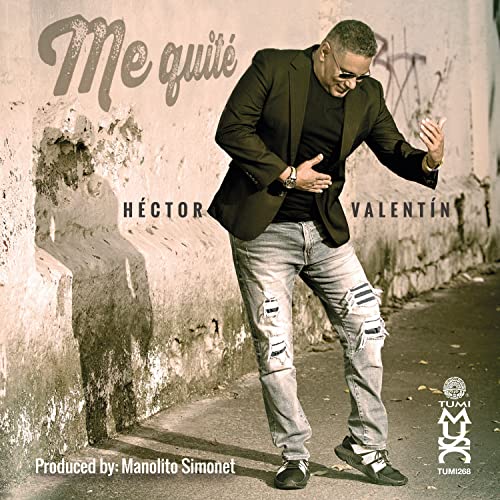 Héctor Valentín in black jacket and ripped jeans, posing against a wall.