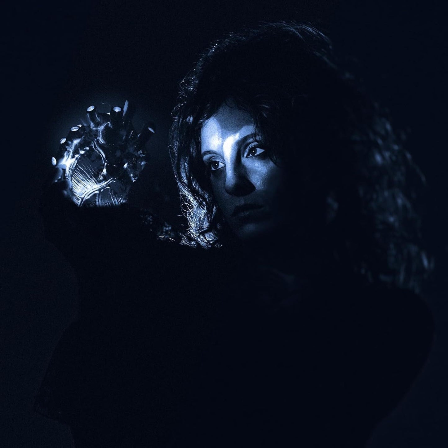 Dark portrait of a woman holding a glowing, anatomical heart.