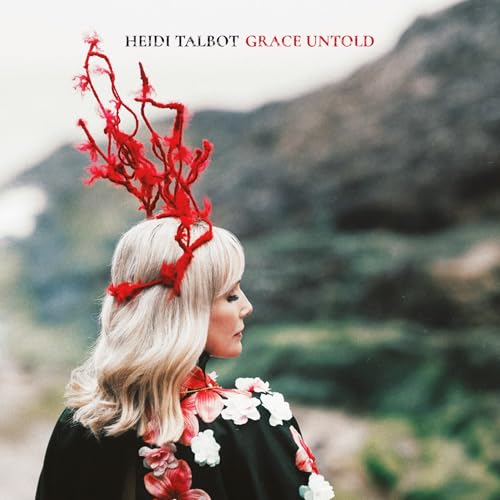 Heidi Talbot wearing a red branch headpiece and floral cape against a blurred landscape.