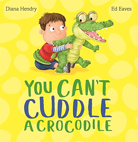 Boy attempts to hug a large, smiling green crocodile on yellow polka dots.