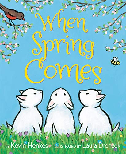 Three white bunnies sit in green grass under a blue sky with flowering branches.