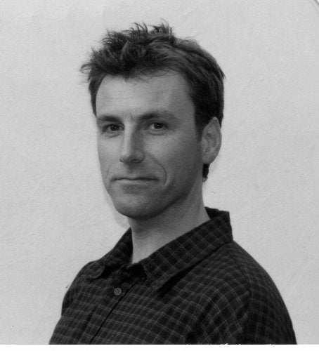 Black and white headshot of a man with short, spiky hair.