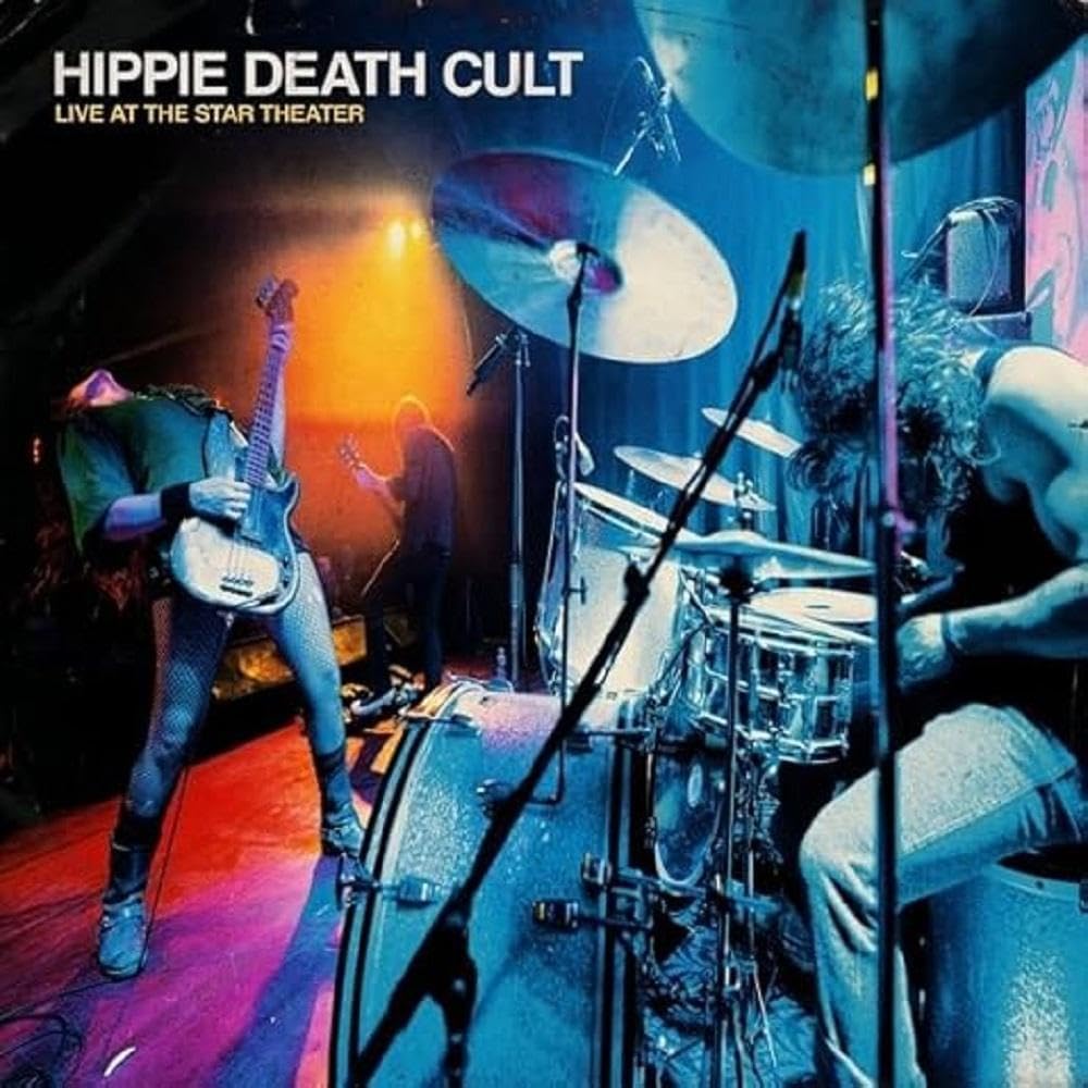 Band performing live on stage with drums, guitars, and stage lighting.