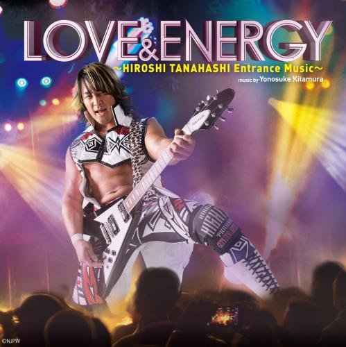 Hiroshi Tanahashi playing an electric guitar on stage before a crowd with colorful lights.