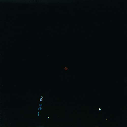 Dark album cover with a small red cross and blurred city lights.