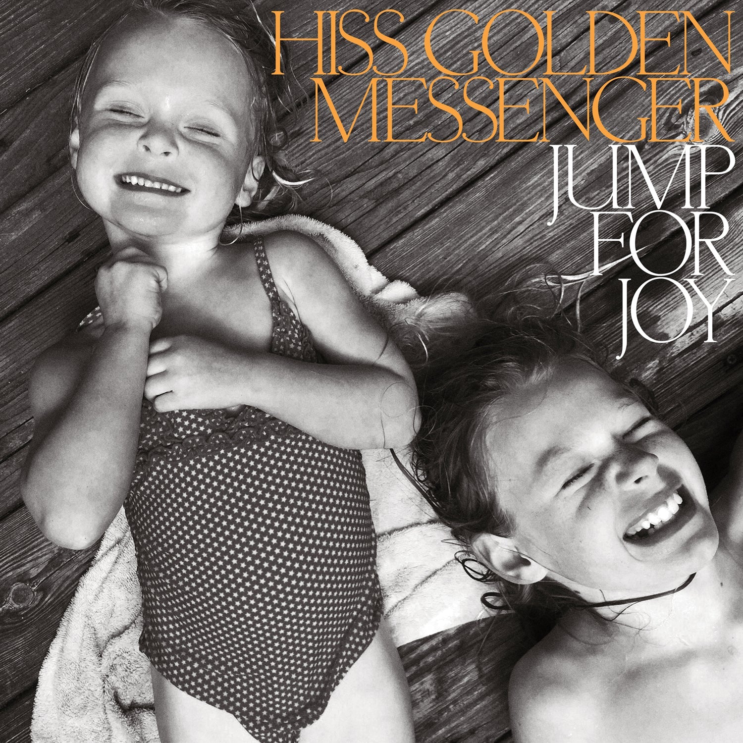 Album cover: two laughing children lying on wooden planks.