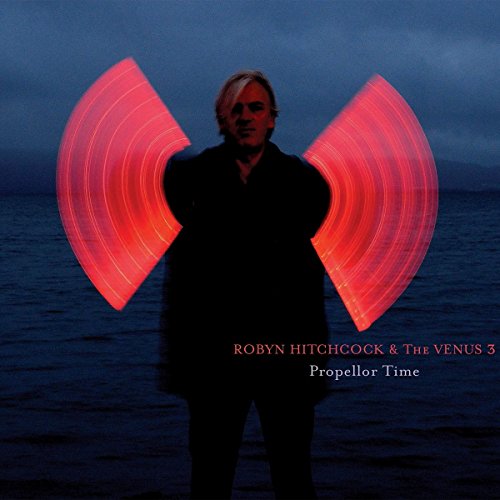 Album cover: man with blurred red propeller-like shapes, dark background.