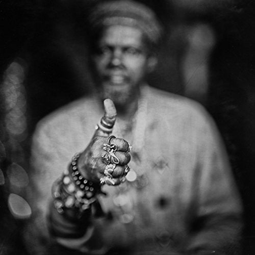 Black and white portrait of Lonnie Holley with raised hand and rings.