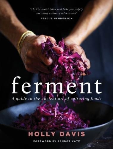 Hands holding shredded red cabbage over a bowl on a book cover titled Ferment.