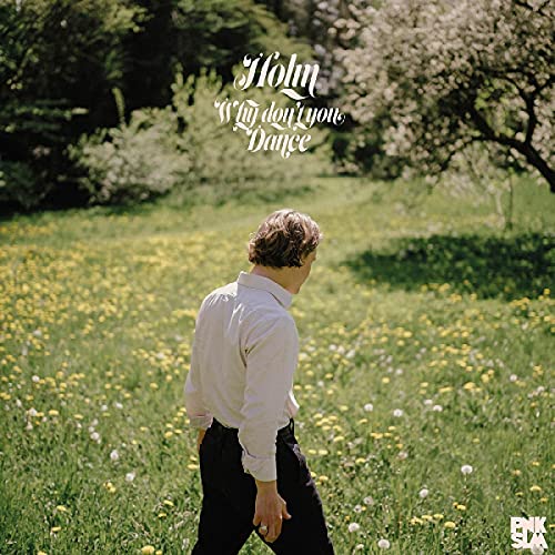 A man in a light shirt walks through a field of yellow flowers.
