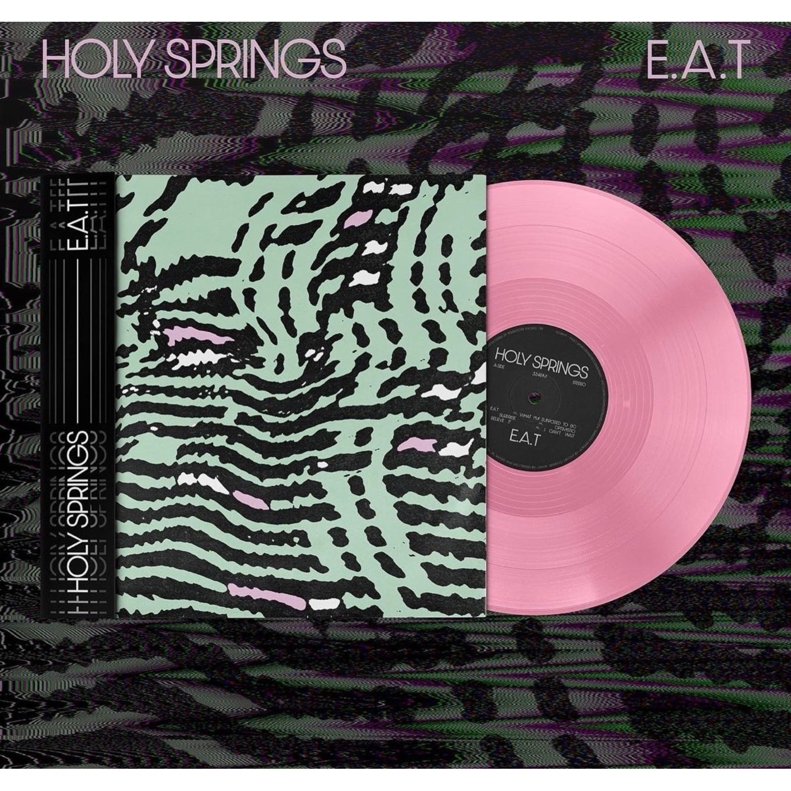 Vinyl record cover with abstract black and green pattern next to a pink disc.