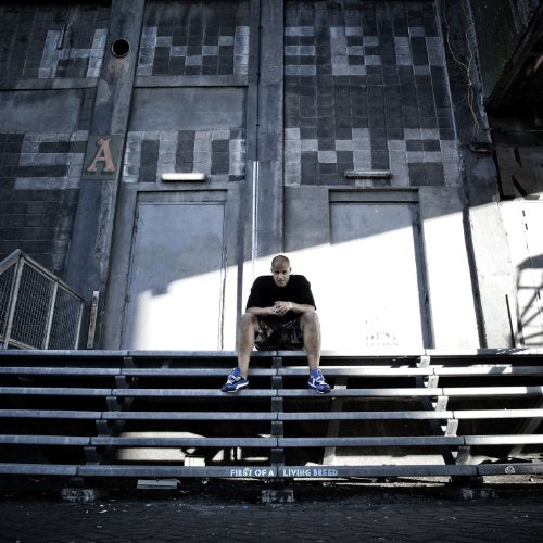Man sitting on bleachers in front of a textured, gray building.