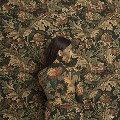 The image shows a woman camouflaged in a floral patterned wallpaper, facing right.