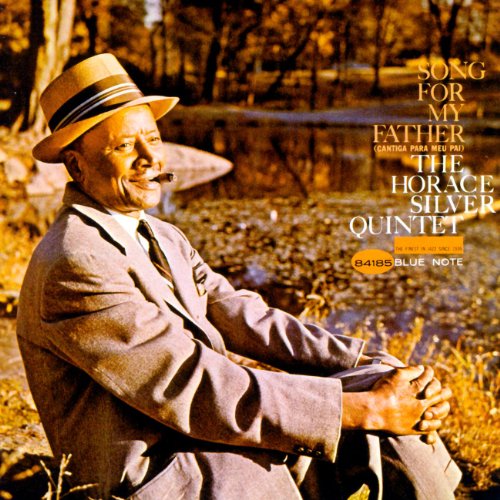 A man in a suit and fedora sits outdoors near water, with album text overlay.