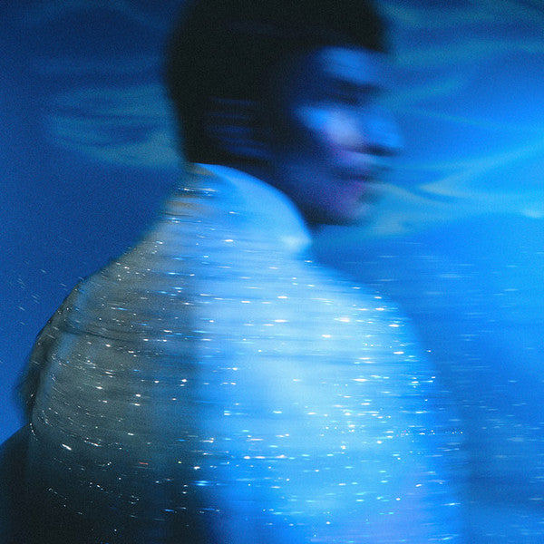 Blurred blue image of a person, likely album cover art.