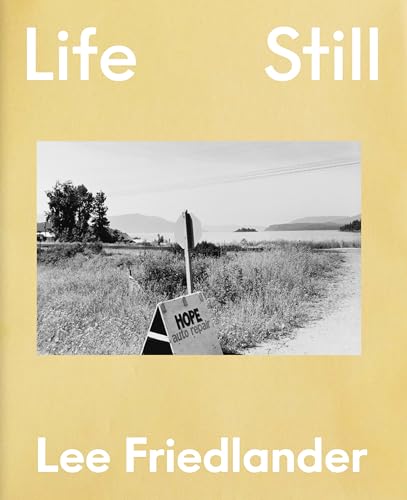 Book cover with black and white landscape photograph, roadside sign visible.