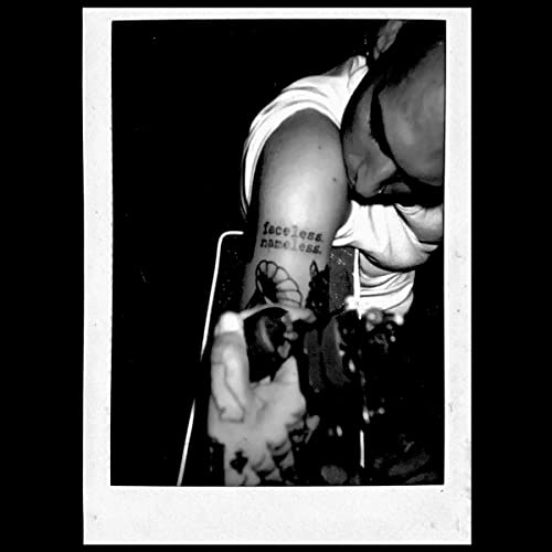 Black and white photo of a person with face obscured, holding a vinyl record.