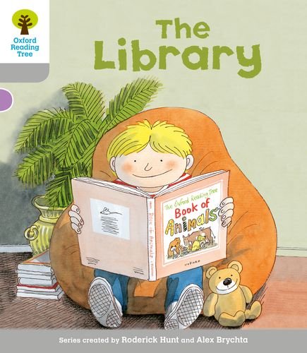 Boy reading a book in an armchair with a teddy bear nearby.
