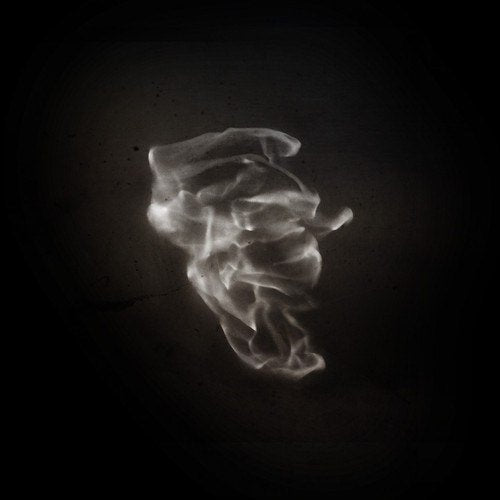 Ghostly, abstract face formed from smoke against a dark background.