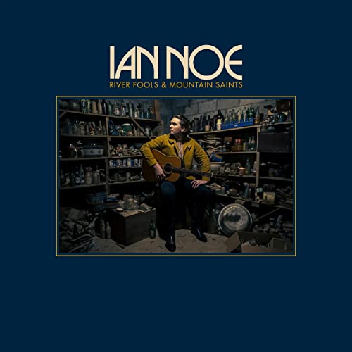 Ian Noe album cover: musician with guitar in cluttered room.