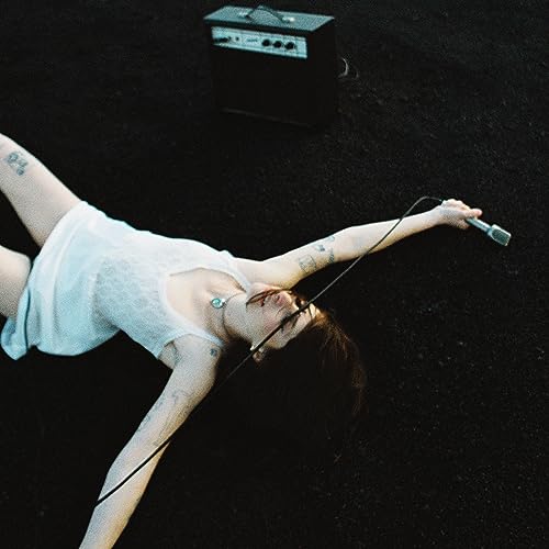 Woman with tattoos lying with a microphone and amplifier.