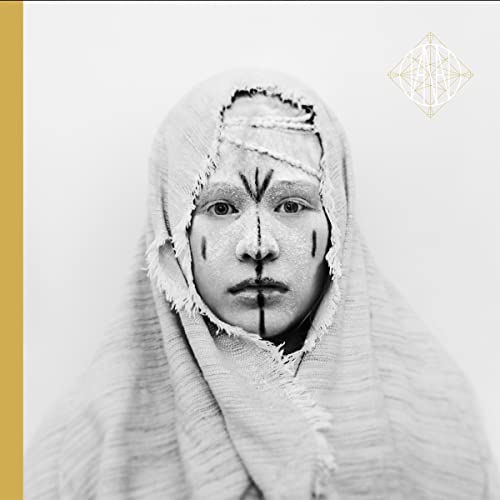 Black and white portrait of a person with face markings and a headwrap.
