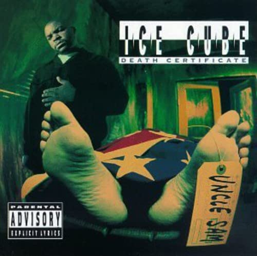 Ice Cube stands over a body covered by a flag with a toe tag.
