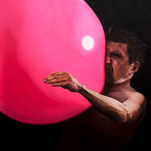Man straining to inflate a large, bright pink balloon.