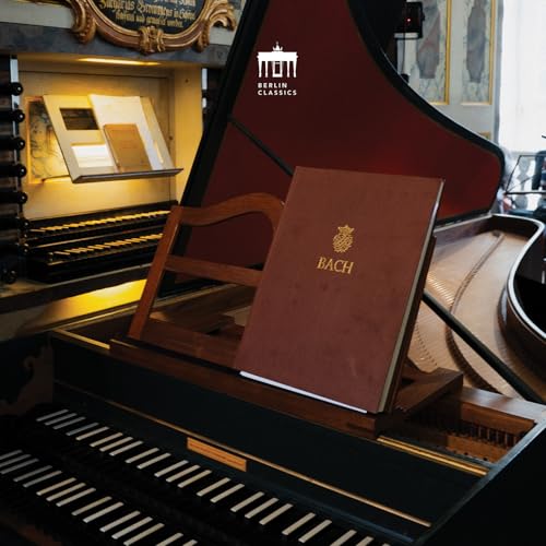 Brown CD case with "BACH" on a music stand before a piano.