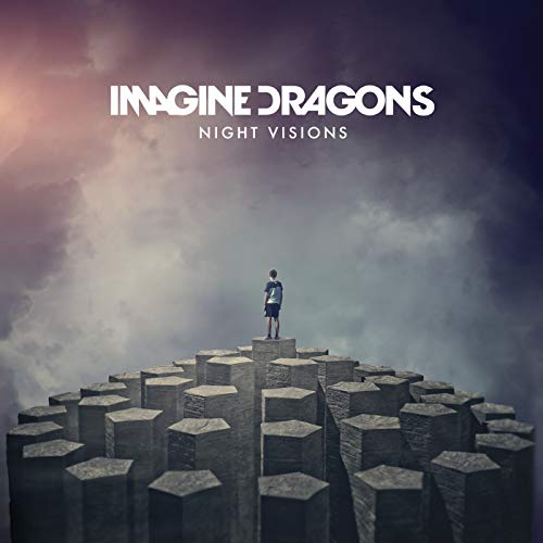 A person stands on a hexagonal stone pillar against a cloudy, dark sky.