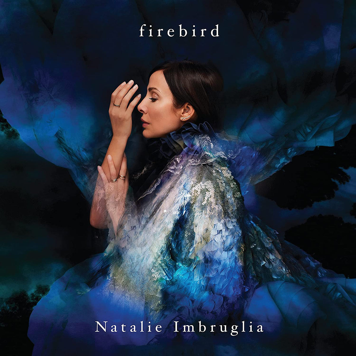 Natalie Imbruglia album cover featuring a woman in a blue dress with dark background.