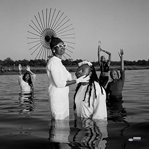 Black and white photo of four people in water with a large wheel.