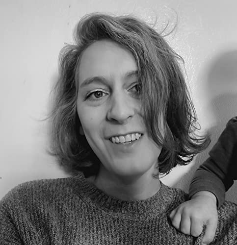 Black and white portrait of a smiling person with shoulder-length hair wearing a sweater.