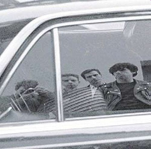 Black and white photo of four people seen through a car window.