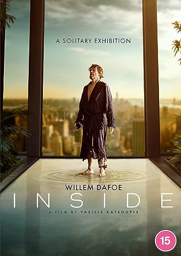 Willem Dafoe stands in a shallow pool inside a room overlooking a city skyline.