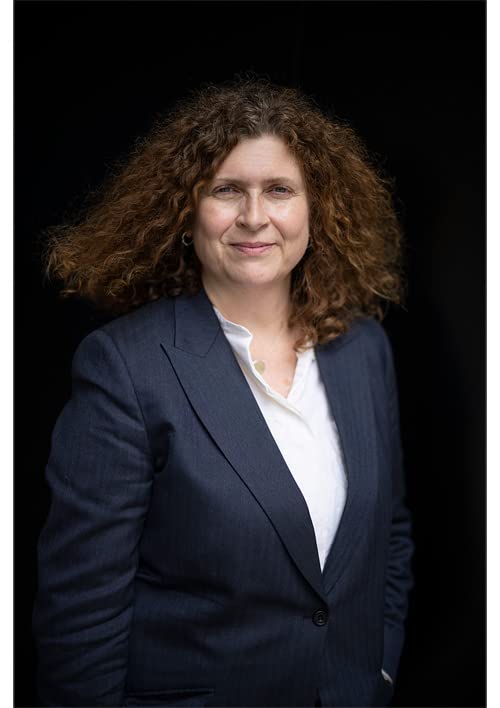 Portrait of a woman with curly hair wearing a dark suit.