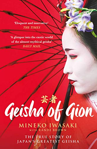 A geisha in traditional makeup and kimono stands before a large red parasol.