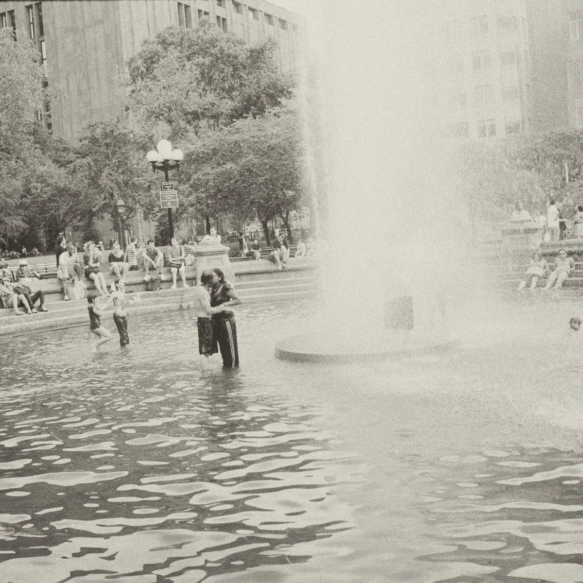 Black and white photo of a couple embracing in a fountain.