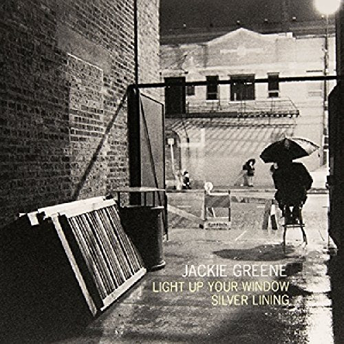 Black and white street scene featuring a person with an umbrella in an alleyway.