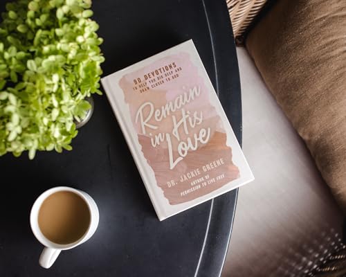 White devotional book, "Remain in His Love," with coffee and greenery.