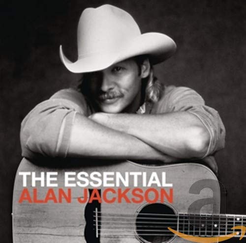 Alan Jackson in a cowboy hat holding an acoustic guitar.