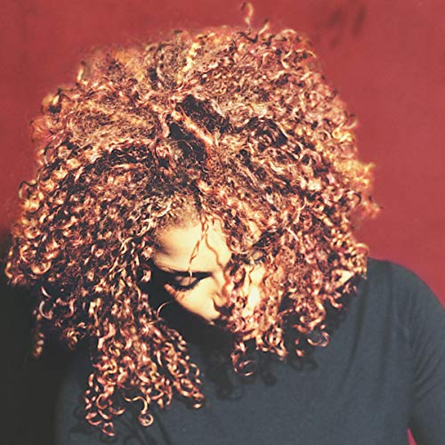 Janet Jackson with voluminous curly hair looking down against a red background.