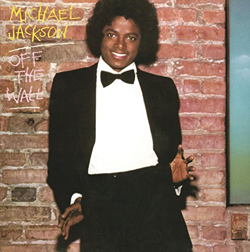 Michael Jackson in a tuxedo leaning against a brick wall.