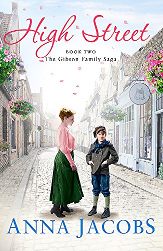 A woman and a young boy stand on a cobblestone street in a historic town.