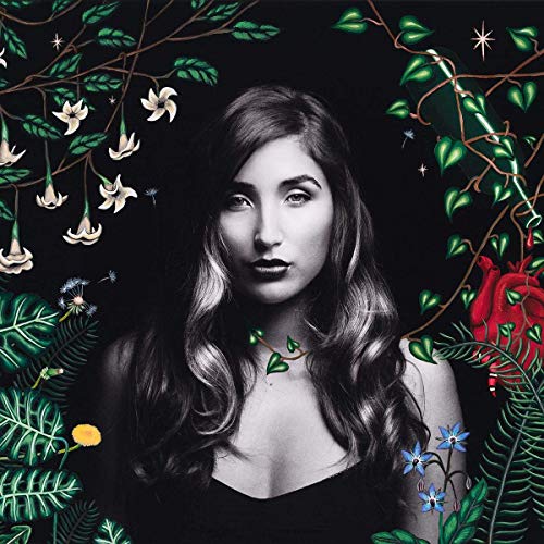 Black and white portrait of a woman surrounded by colorful flowers and foliage.