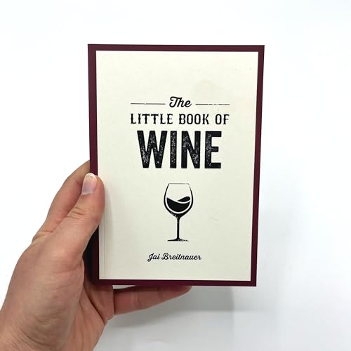 Small book titled “The Little Book of Wine” held in a hand.