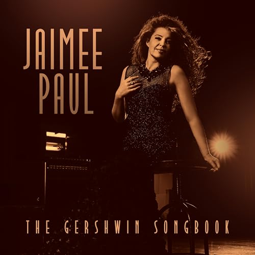 Jaimee Paul posing on a stool in a sepia-toned studio setting.