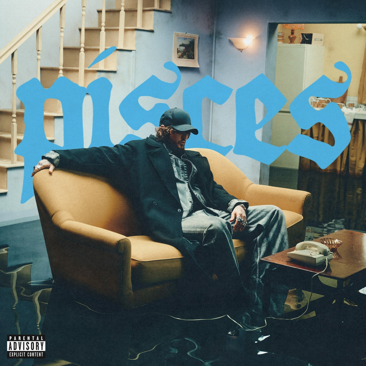 James Arthur album cover: man in black coat sits on yellow couch.